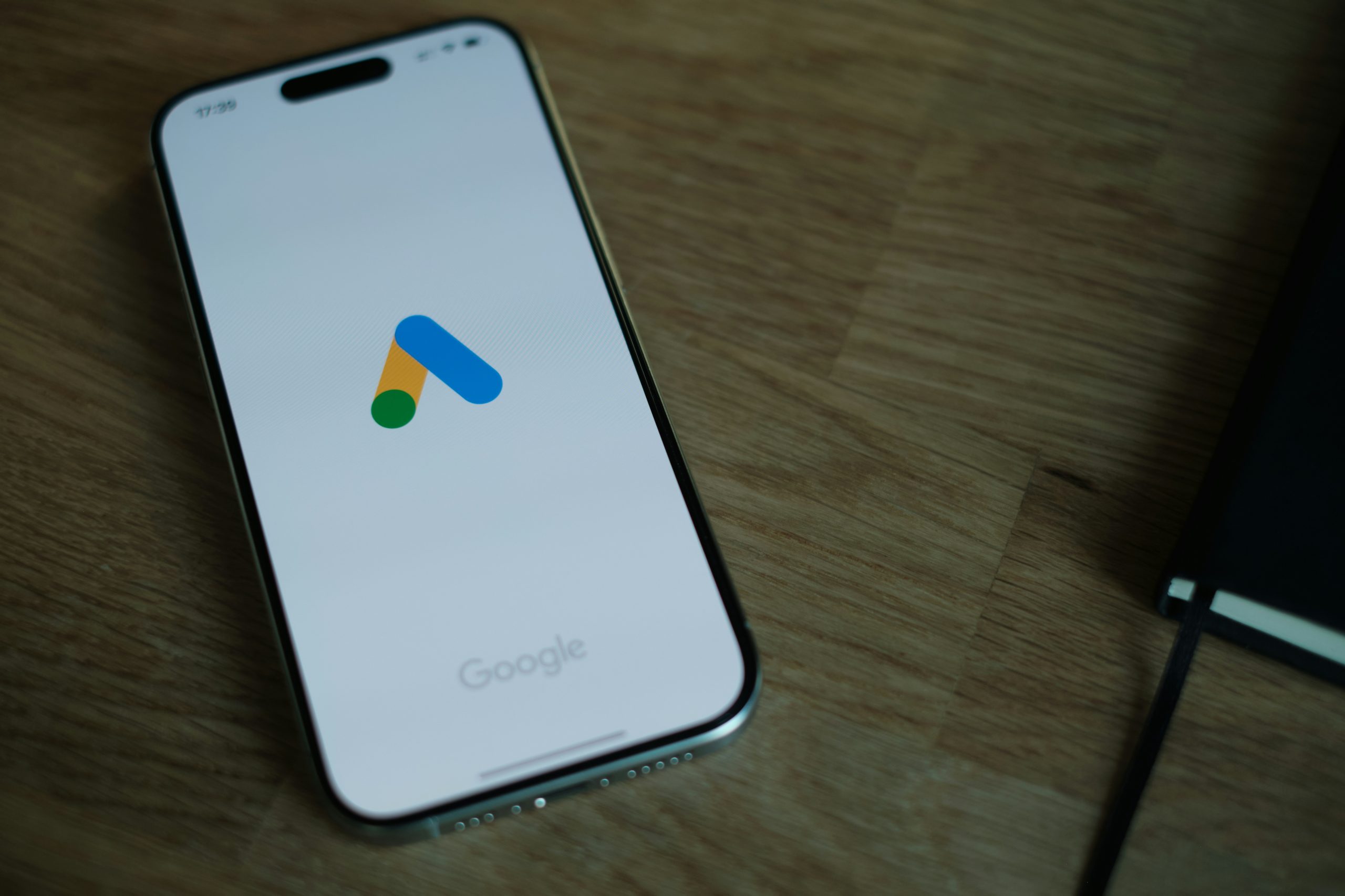 Smartphone displaying the Google Ads logo on a wooden desk, representing digital advertising and PPC campaign management.